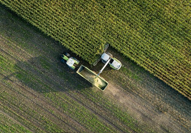 Aerial top view of tractor and harvester working in a field.