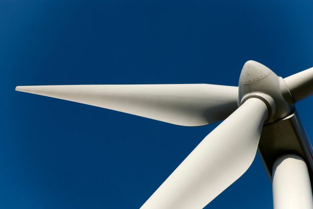 Close up of a wind turbine head against a blue sky.