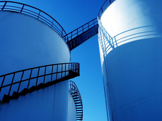 Shot of two water warehouses connected against blue sky.