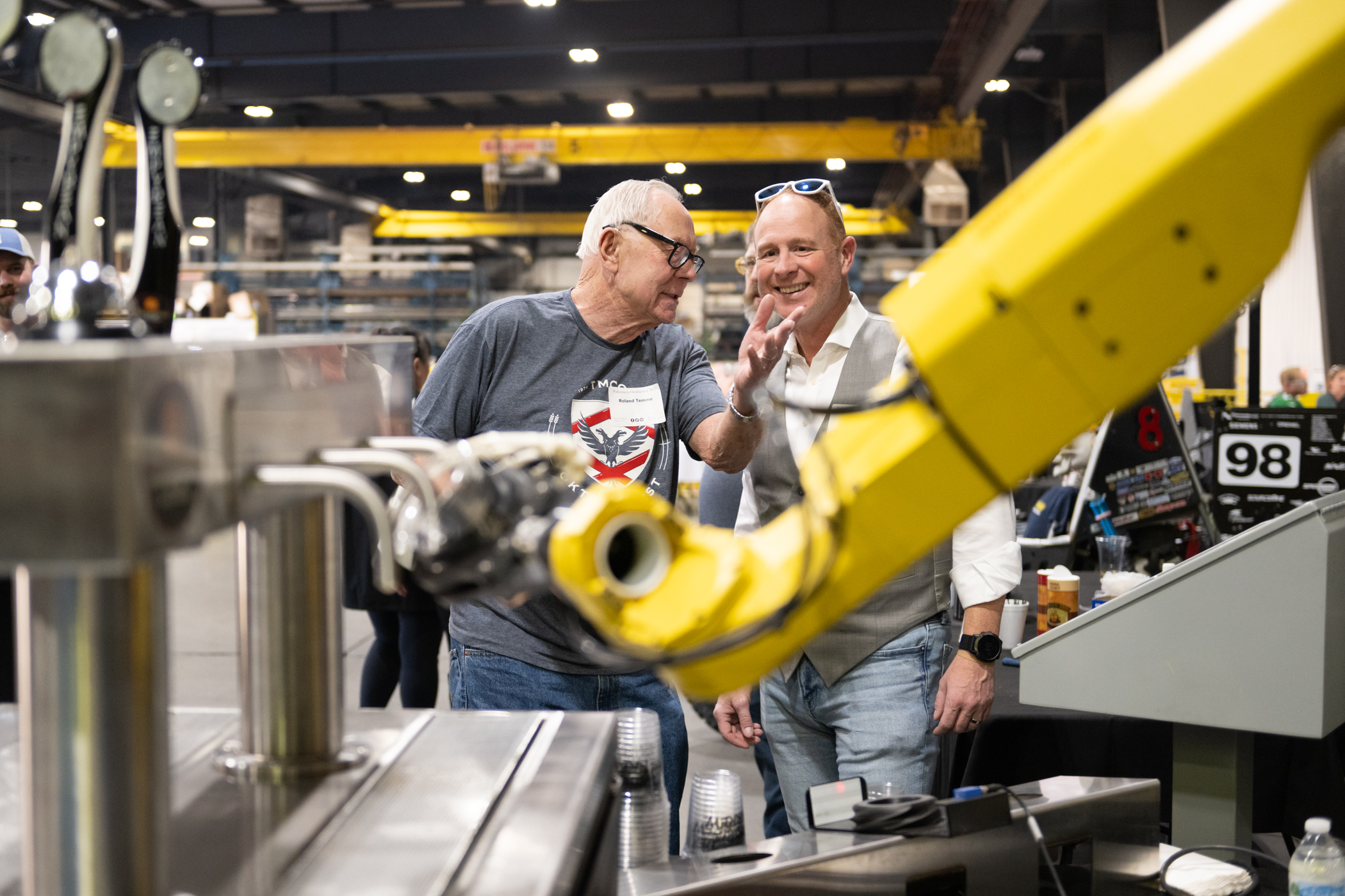 Chairman Roland Temme talking with a man in a workshop.
